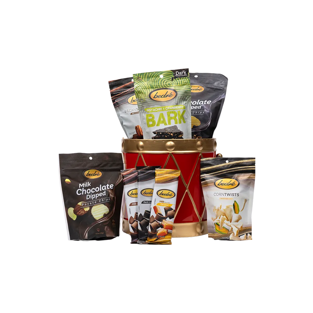 Bedré Fine Chocolate red and gold Christmas Drum tin (large) styled with Milk Chocolate Melts Hot Fudge, Pistachio Cranberry Bark, mini chocolate bars, and Corn Twists pouches