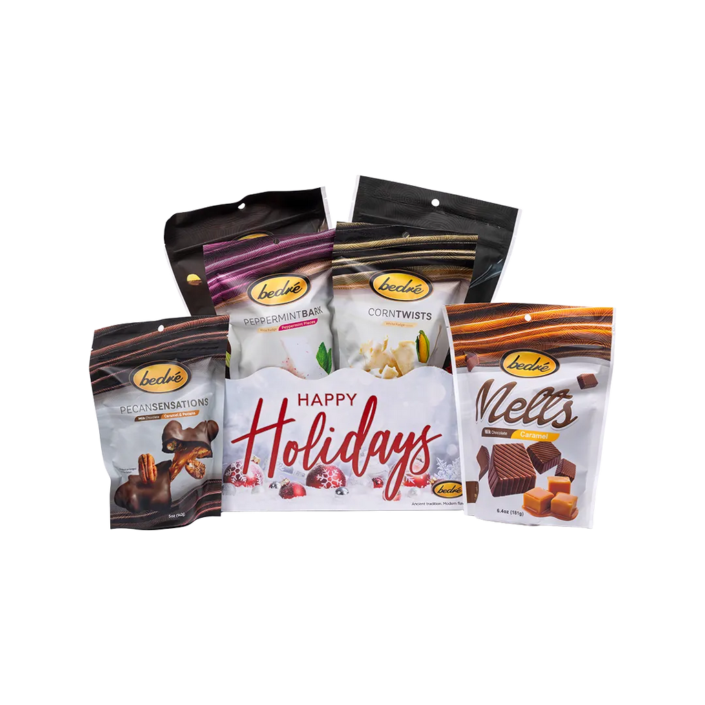 Happy Holidays snow-themed gift box with Bedré Pecan Sensations, Peppermint Bark, and Corn Twists pouches standing behind it, full white background margin on all sides