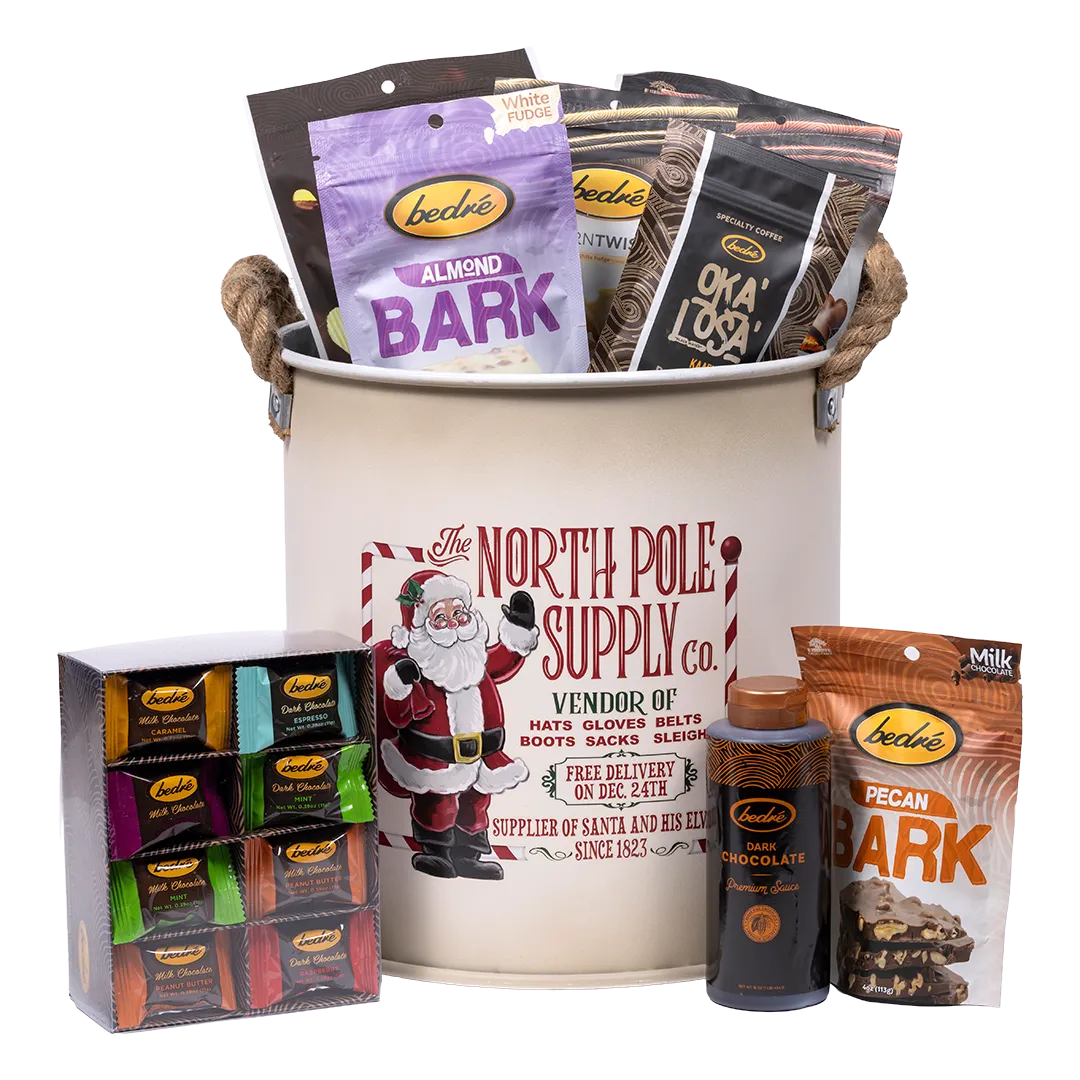 Bedré Fine Chocolate North Pole Supply Co. canister styled with a boxed Melts assortment, Dark Chocolate Premium Sauce, and Pecan Bark displayed alongside